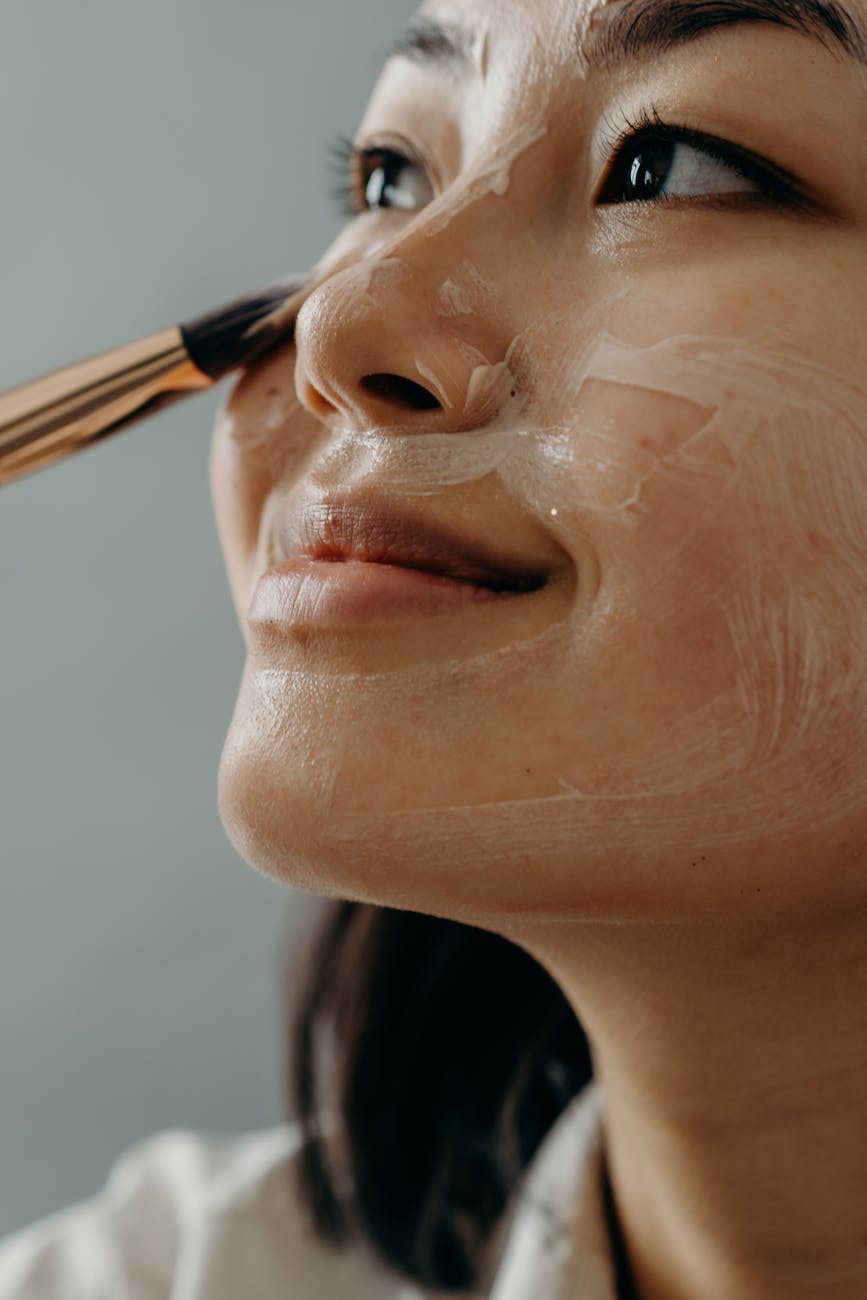 a close up shot of a woman applying a cream on her face